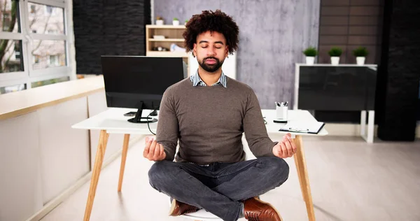 African American Male Meditation In Office Near Computer