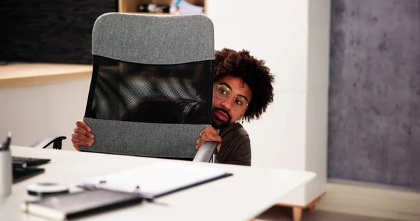Scared Man Hiding Behind Office Desk In Room