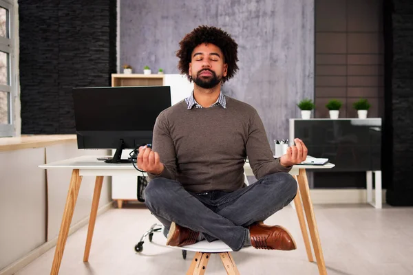 African American Male Meditation In Office Near Computer