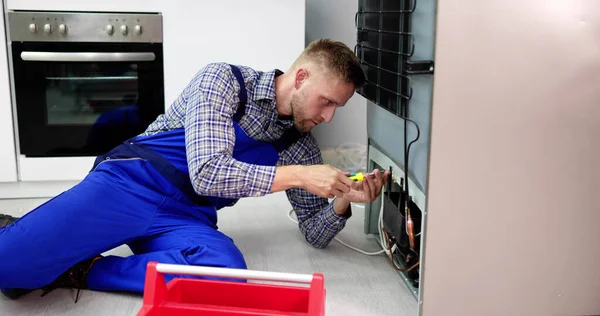 Cropped Image Of Serviceman Working On Fridge With Screwdriver At Home