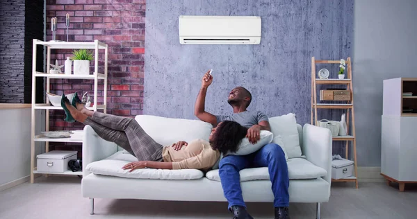 Happy Family Couple Using Air Conditioner. Apartment AC