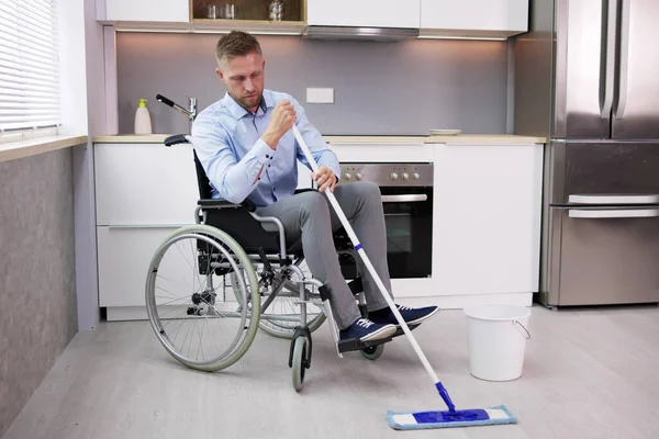使用拖把清洁厨房地板的残疾人士 — 图库照片