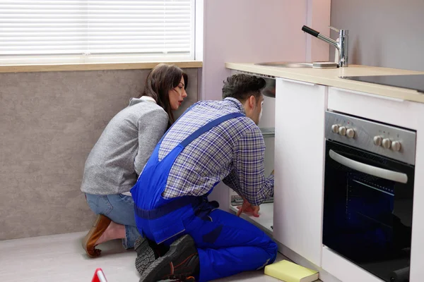 キッチンパイプ配管損傷の問題 修理工と女 — ストック写真