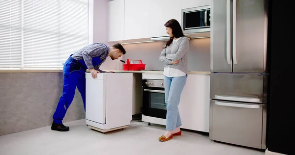 食器洗い機アプライアンスのインストール 修理工が洗濯機を動かす — ストック写真