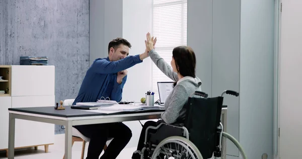 Businesswoman With Disability Giving High Five To Her Partner In Office