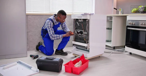 アフリカの修理人食器洗い機のアプライアンスを修復します 電気チェック — ストック写真