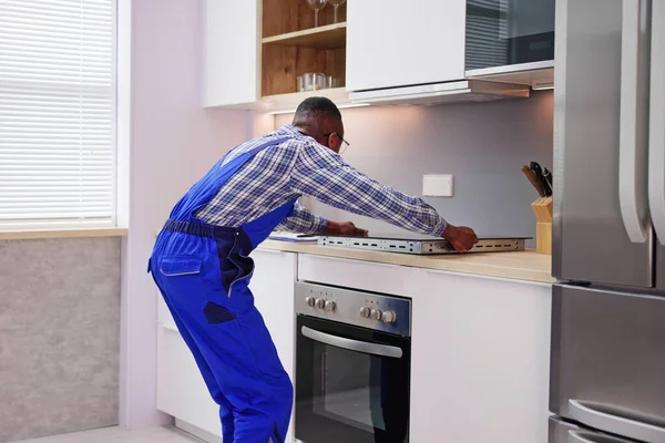 Jovem Africano Reparador Examinando Fogão Cozinha — Fotografia de Stock