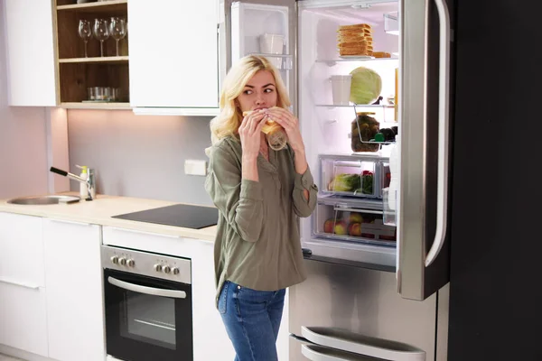 Hambrienta Mujer Comiendo Sandwich Queso Cerca Refrigerador Abierto — Foto de Stock