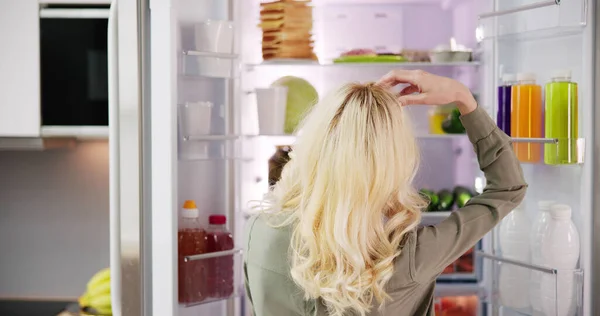 家で台所で食べ物を探している空腹の女性 — ストック写真