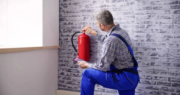 Worker Installing Fire Extinguisher. Inspection Service. Checking Security Label