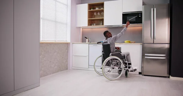 利用抓斗工具控制厨房微波的残疾人 — 图库照片