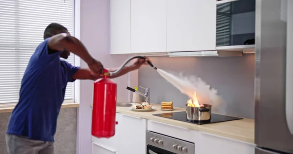 Adam Mutfakta Yanan Tencereyi Söndürmek Için Yangın Söndürücü Kullanıyor — Stok fotoğraf