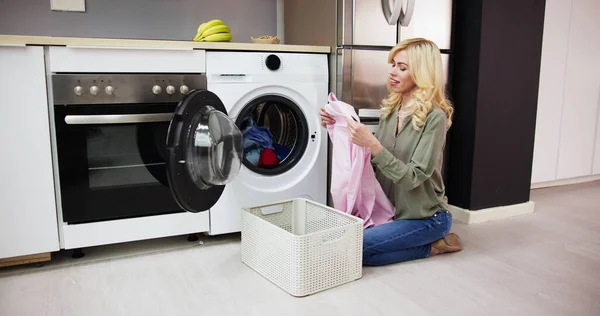 女人们在洗衣房的电子洗衣机附近闻到干净衣服的味道 — 图库照片