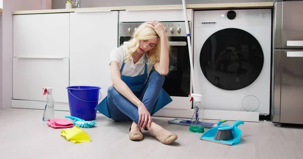 Mujer Joven Frustrada Sentada Piso Cocina Mirando Productos Limpieza Casa —  Fotos de Stock