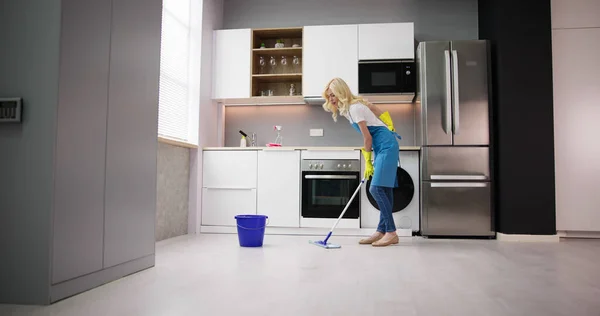 幸福的女人在家里清洗用拖把在厨房地板 — 图库照片