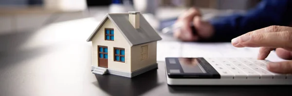 Person Hand Doing Property Tax Calculation Using Calculator House Model — Stock Photo, Image