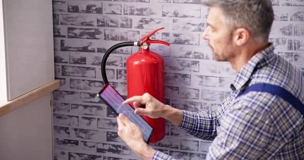 Worker Installing Fire Extinguisher. Inspection Service. Checking Security Label