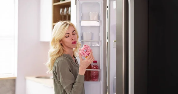 Женщины Едят Пончики Рядом Холодильником Кухне — стоковое фото