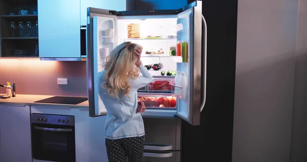 オープン冷蔵庫で夜の空腹の女性 — ストック写真