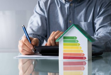 Midsection işadamı ile enerji verimli grafik Office Ev modeli üzerinde fatura hesaplama