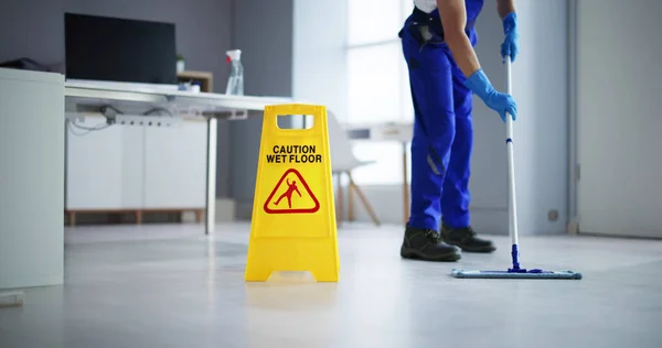 低断面男清洁工清洁地板 小心湿地板标志在办公室 — 图库照片
