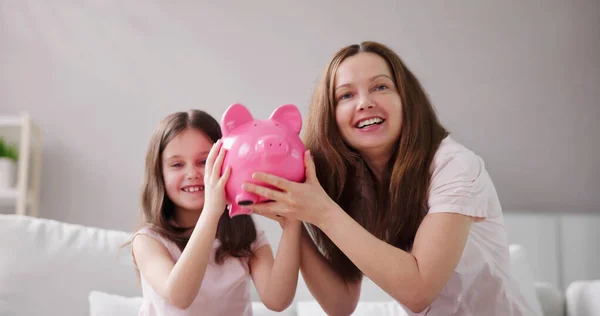 ピギーバンクでお金を節約する母親と子供 — ストック写真