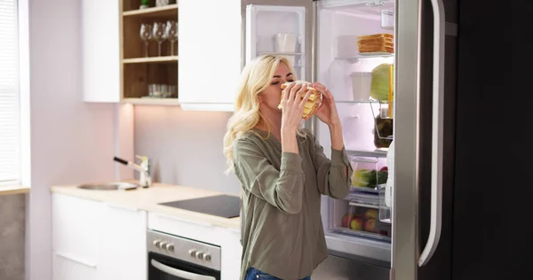 Молода Жінка Їсть Сендвіч Перед Холодильником — стокове фото