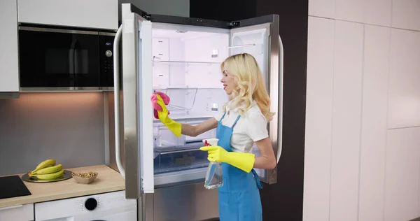 Νέος Χαμογελαστός Επαγγελματικό Καθαρισμό Υπηρεσία Γυναίκα Καθαρισμού Ψυγείο Στην Κουζίνα — Φωτογραφία Αρχείου