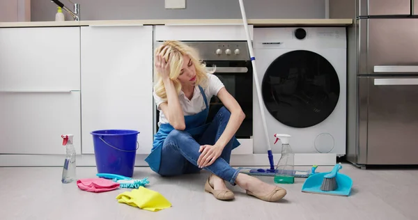 Mujer Joven Frustrada Sentada Piso Cocina Mirando Productos Limpieza Casa —  Fotos de Stock