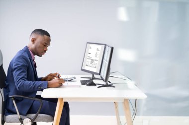 İş yerindeki bilgisayardan faturayı kontrol eden bir iş adamının yan görüntüsü