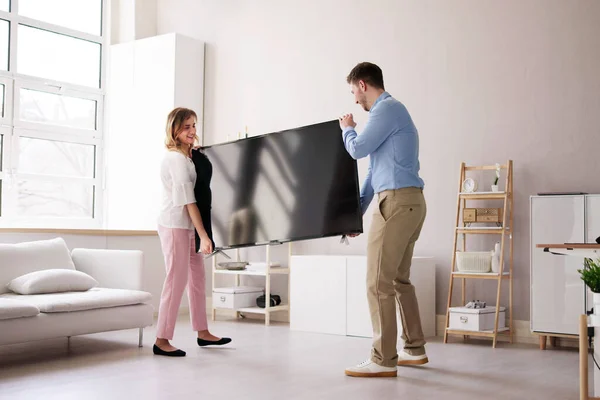 Souriant Jeune Couple Portant Une Nouvelle Télévision Maison — Photo