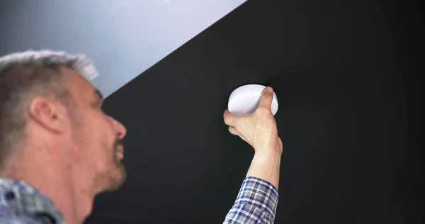 自宅の天井壁に煙探知機を設置する人の手 — ストック写真