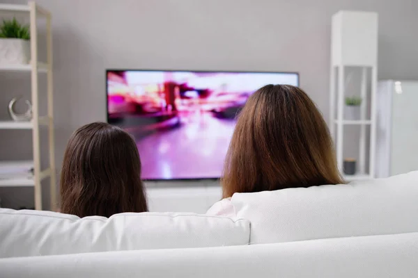 笑顔の母と娘は自宅でテレビを見て — ストック写真