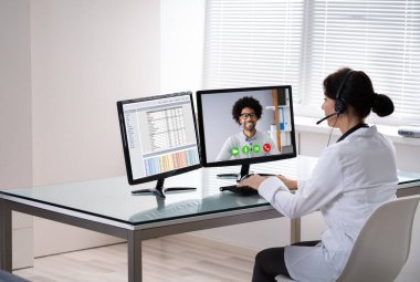 Doctor Talking To Patient Through Video Chat On Laptop At Desk clipart