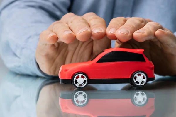 Mão Empresário Protegendo Carro Brinquedo Vermelho Mesa Reflexiva — Fotografia de Stock
