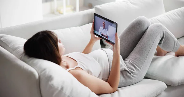自宅でタブレットPcで医師と若い妊婦ビデオ会議 — ストック写真