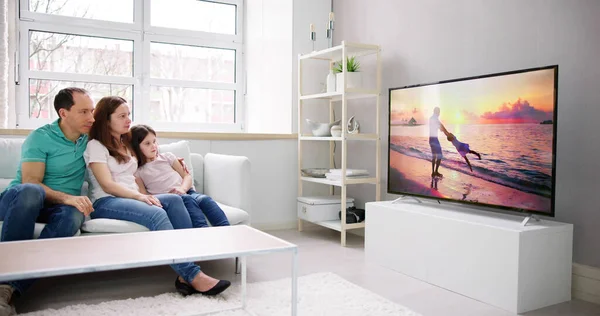 Молодая Семья Смотрит Телевизор Вместе Дома — стоковое фото