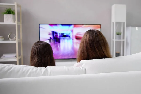 笑顔の母と娘は自宅でテレビを見て — ストック写真