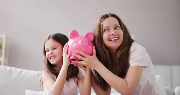 ピギーバンクでお金を節約する母親と子供 ストック画像
