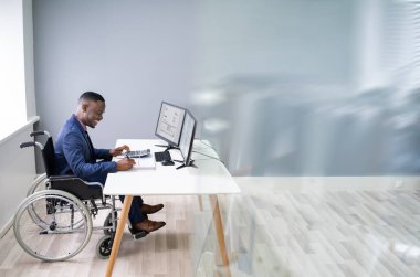 Tekerlekli sandalyedeki bilgisayarda çalışan engelli Afrikalı Muhasebeci