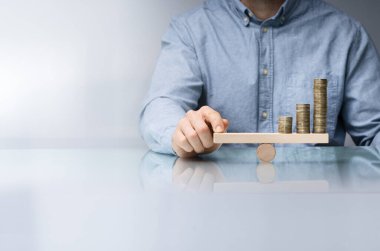 Yakın çekim Dengeleme bir işadamının'ın el parmak ile ahşap tahterevalli sikkelerinde Resepsiyon üzerinde yığılmış.