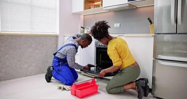 Trabalhador Masculino Reparando Aparelho Forno Presença Mulher Jovem Sala Cozinha — Fotografia de Stock