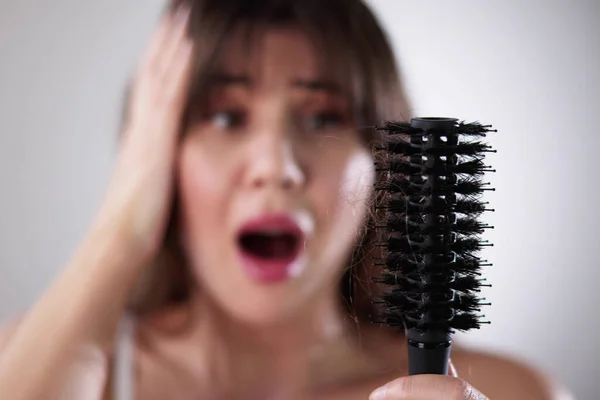 Молода Жінка Халаті Тримає Гребінець Дивлячись Випадання Волосся Вдома — стокове фото