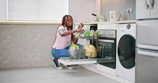 年轻快乐的女人在家里安排板放入洗碗机 — 图库照片