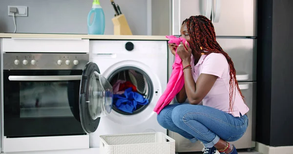 Young Woman Crouching With Cleaned Clothes Near The Electronic Washer