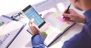Gantt App ve takvim yazma programı ile cep günlüğü ile kalem tutan işadamı