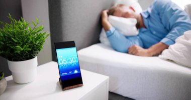 Adam evdeki cep telefonunda alarmla uyanıyor.