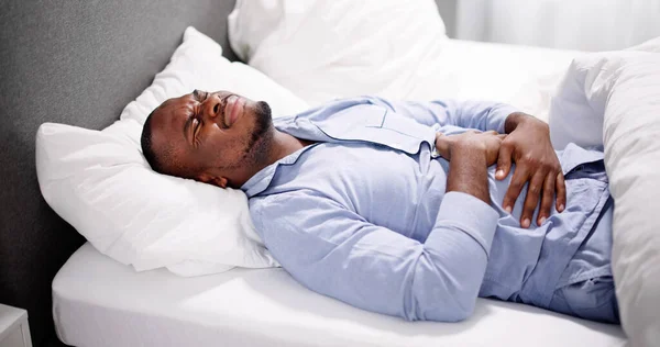 Afrikaner Sitzt Auf Bett Und Leidet Unter Bauchschmerzen — Stockfoto