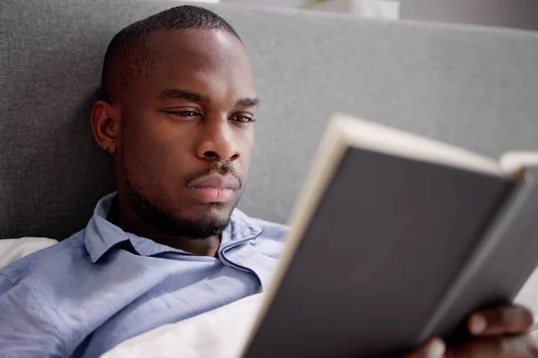 Glücklicher Junger Afrikanischer Mann Liest Sein Buch Auf Dem Bett — Stockfoto