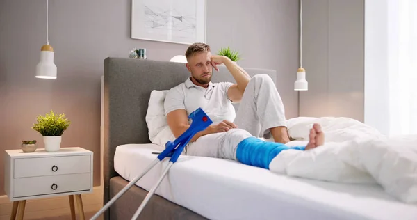 Injured Man Broken Leg Crutches Bed — Stock Photo, Image